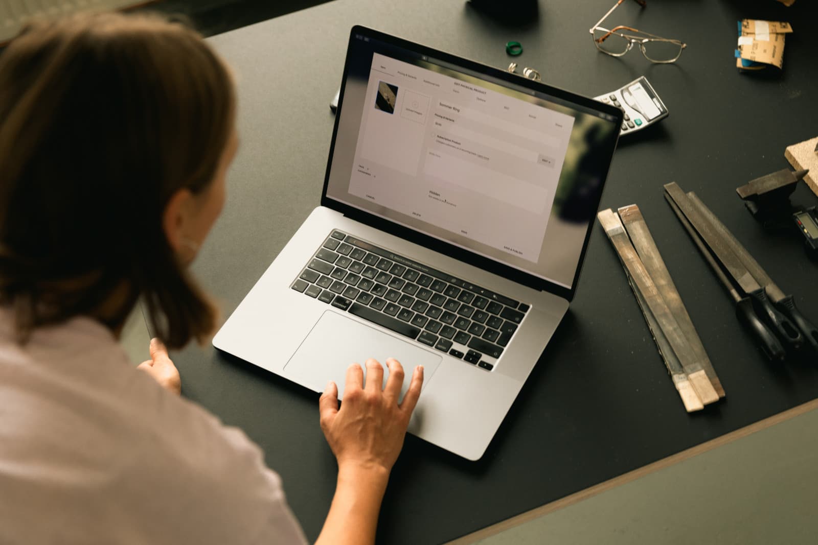 A maker editing an online product listing at a workbench