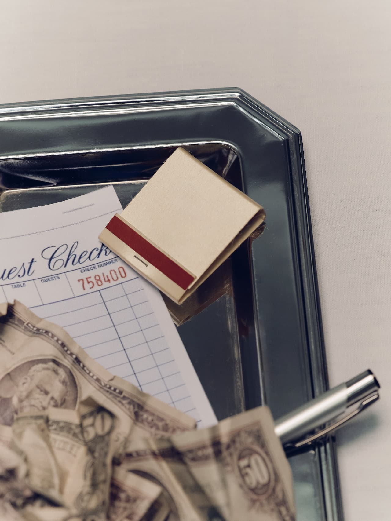 A guest-check bill and cash on a silver tray
