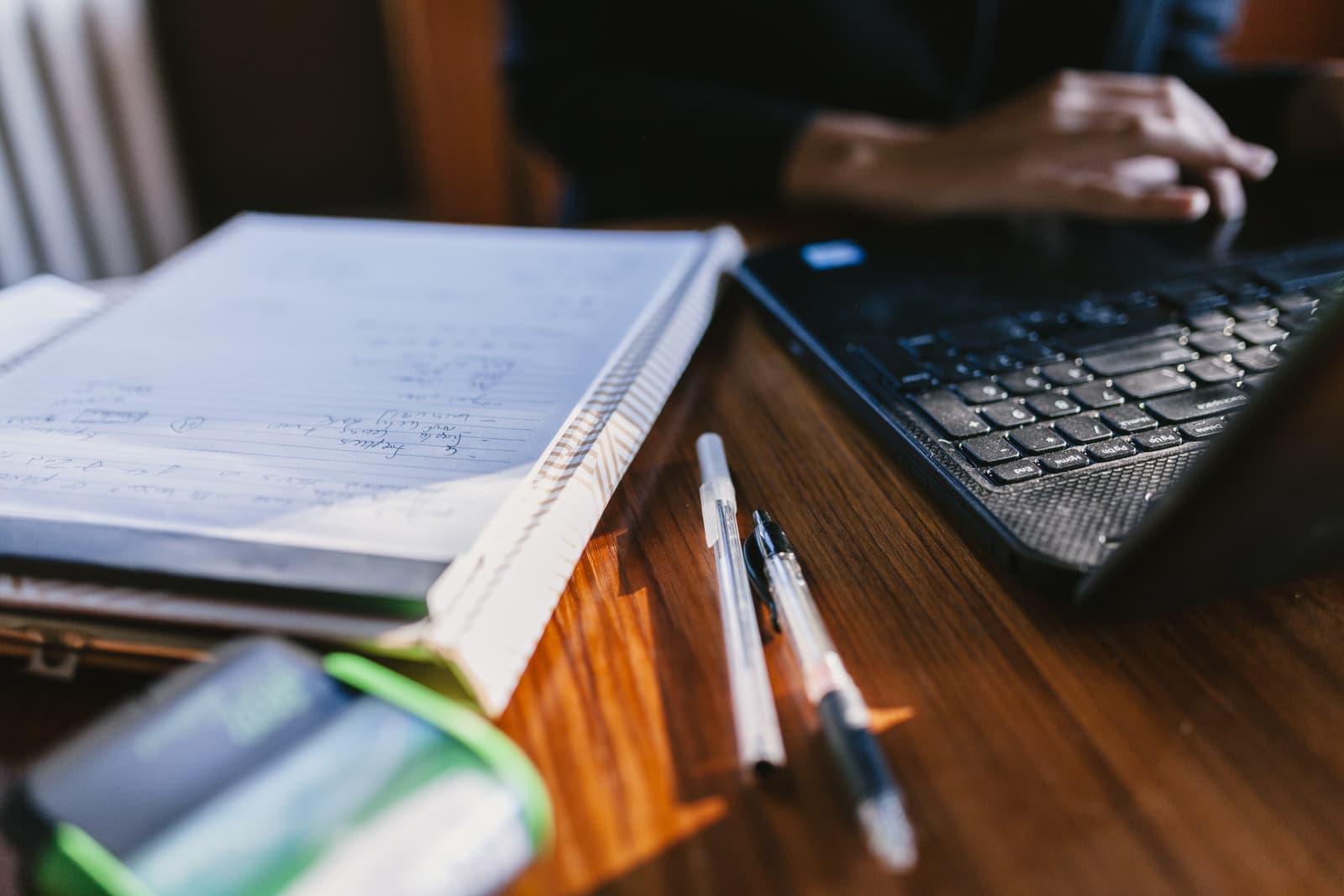 A laptop and handwritten notes on a warm timber desk