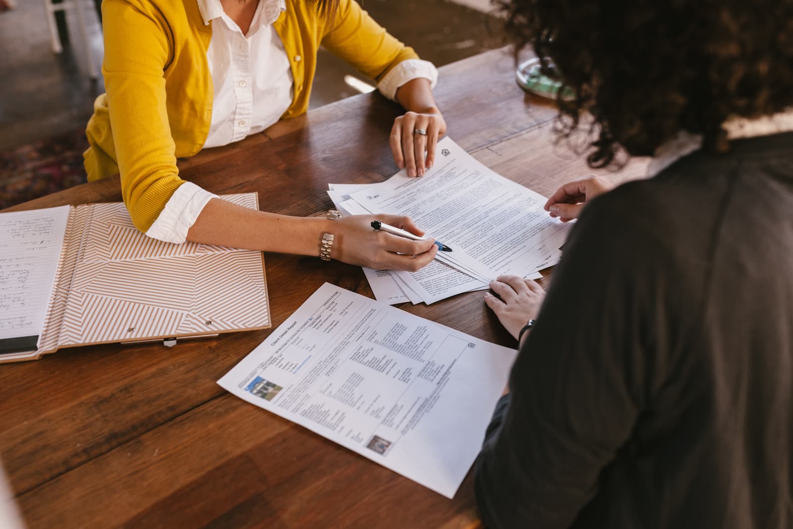 A woman reviewing a contract across the table from a client