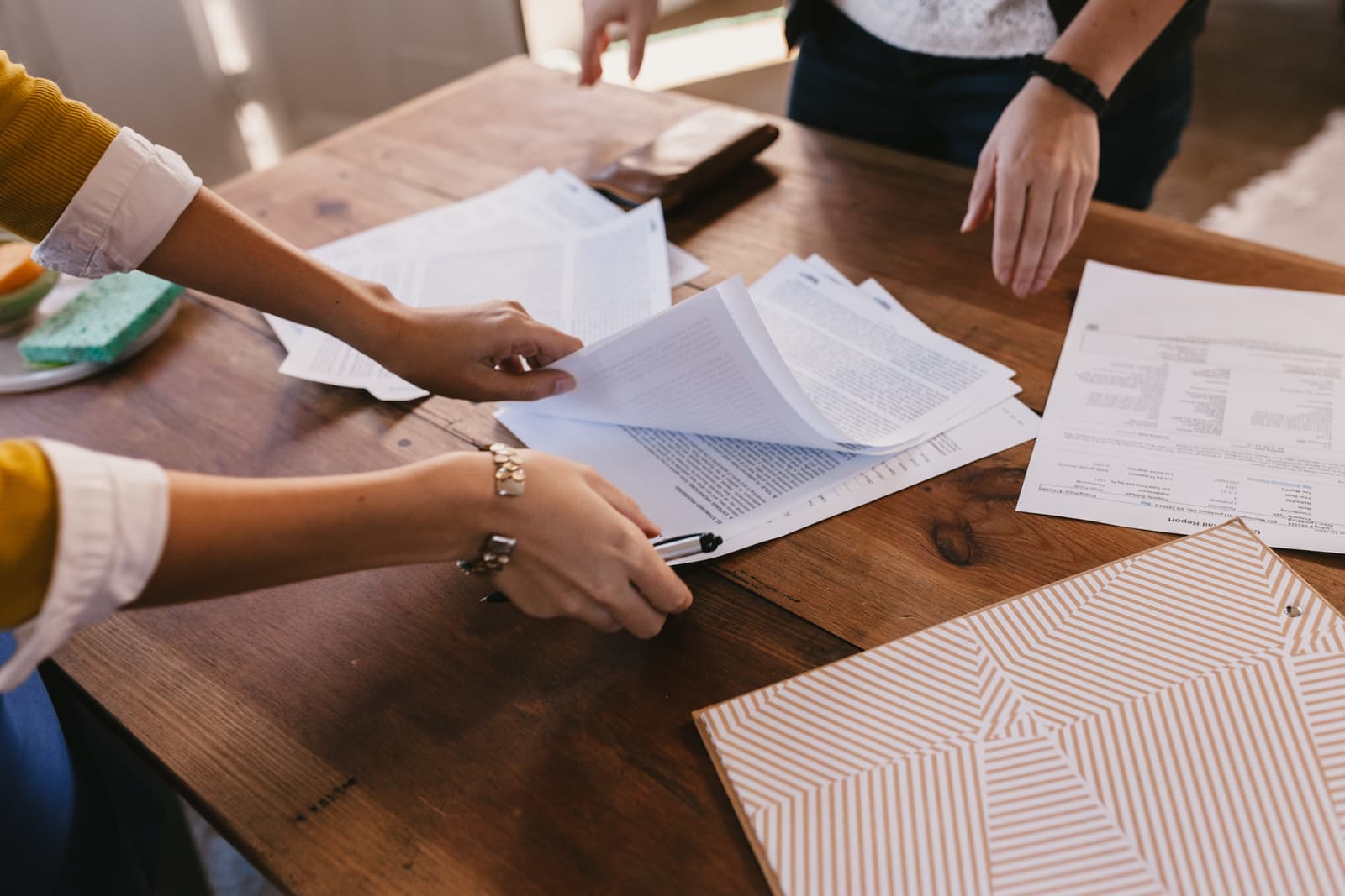 Two people going through paperwork at a warm timber table
